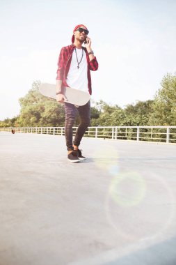 Çocuk holding kaykay ve onun telefonda konuşurken koyu derili