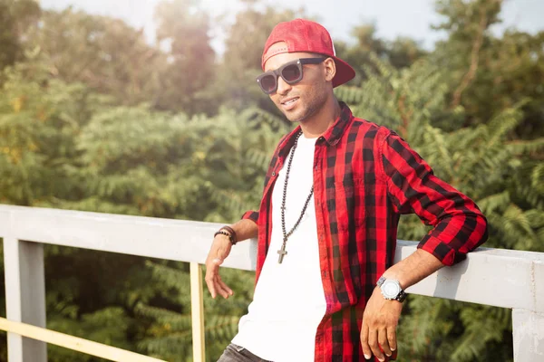 Genç çekici koyu tenli adam arka plan üzerinde ağaçları ile