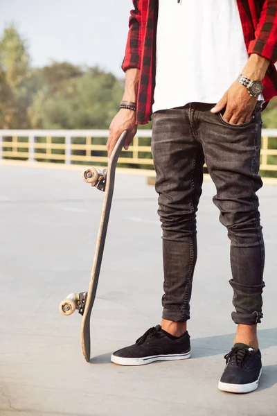 Jovem homem de pele escura segurando o skate — Fotografia de Stock