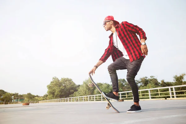 Mörka flådda man bär solglasögon skateboard — Stockfoto