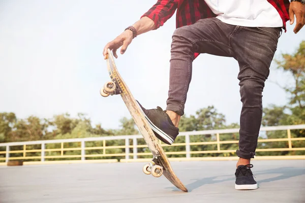 Bijgesneden foto van donkere gevilde jongeman skateboarden — Stockfoto