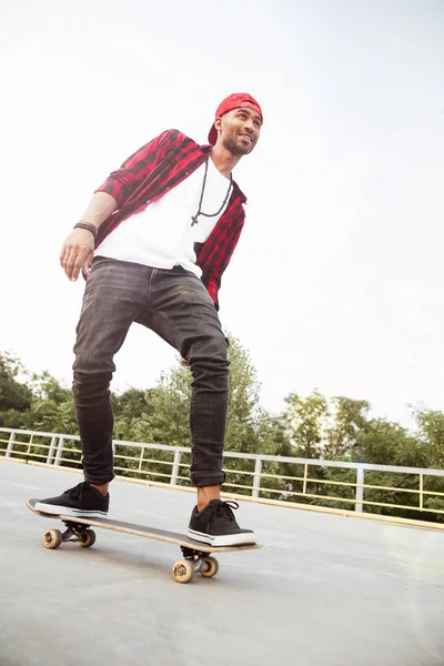 Aantrekkelijke donkere gevilde man skateboarden — Stockfoto