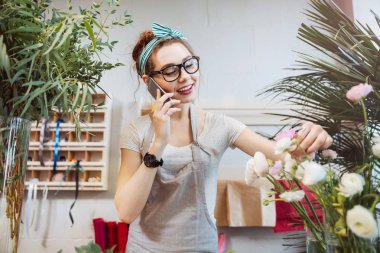 Çiçekçi dükkanı cep telefonuyla konuşan kadın çiçekçi