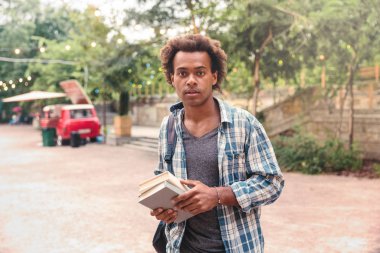 Adam sırt çantası ve parkta duran kitaplar