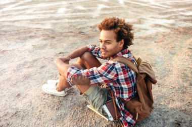 Düşünceli Afrika adam oturmuş ve düşünme sırt çantası ile