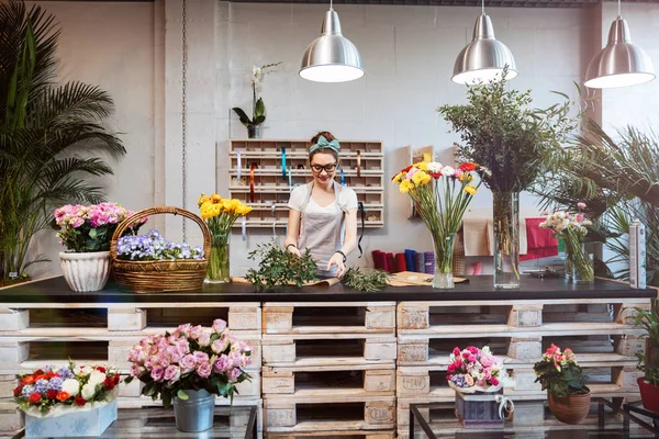 Mujer sonriente florista de pie y trabajando en la florería —  Fotos de Stock