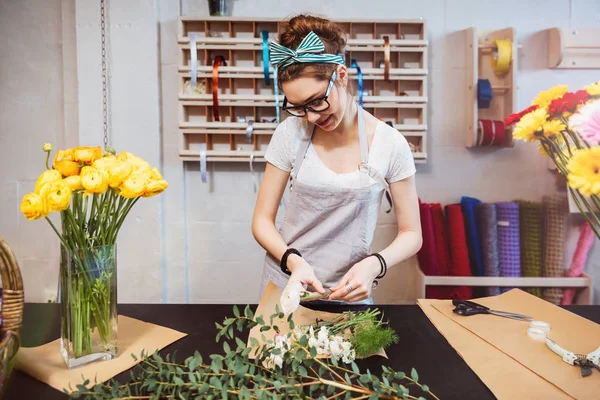 Lachende vrouw bloemist permanent en het maken van boeket in bloemenwinkel — Stockfoto