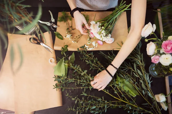 Hands of woman florist creating flower bouquet on table