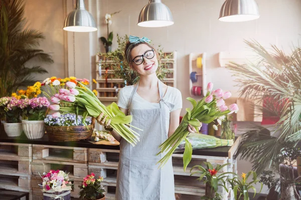 Cheerful woman florist holding two bunches of pink tulips — Stock Photo, Image