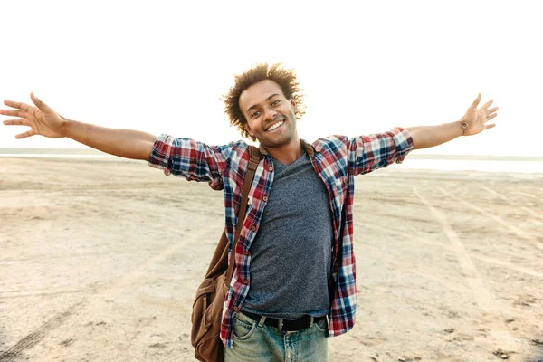 Fröhlicher Mann mit ausgebreiteten Armen am Strand stehend — Stockfoto