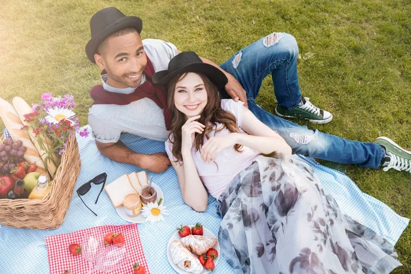 Alegre joven pareja sonriendo y mintiendo teniendo picnic — Foto de Stock