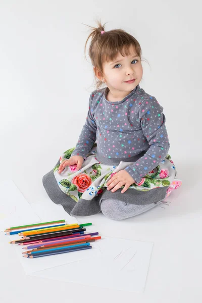 Маленькая очаровательная девочка сидит с карандашами на полу — стоковое фото