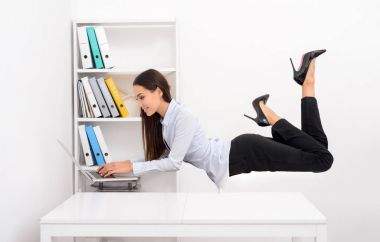 Ofis Masası üzerinde uçan ve dizüstü bilgisayarda çalışan iş kadını