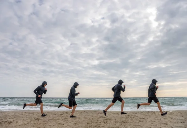 Sport men clones in hoodies jogging at the beach