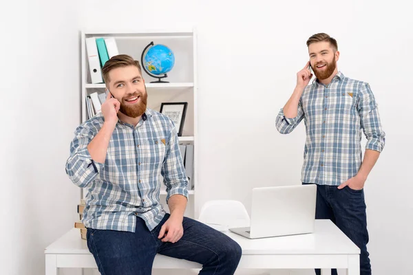 Dos sonrientes hombres de negocios casuales clones hablando por teléfono móvil —  Fotos de Stock