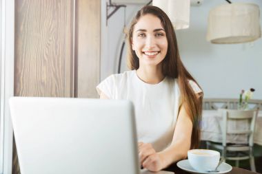 Restoranda dizüstü bilgisayar kullanan çok gülümseyen iş kadın
