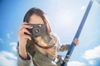 Alarak genç esmer kız holding kamera açık havada çekim