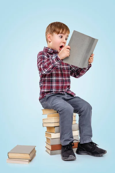 Jongetje lezen boek zittend op stapel boeken — Stockfoto