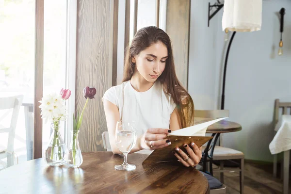 Красивая молодая женщина в ресторане читает меню — стоковое фото