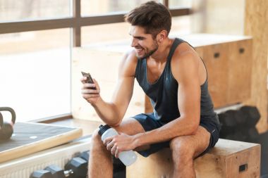 Atletik adam kutunun üstünde oturuyor