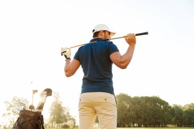 Bir erkek golf oyuncunun kulübü torbayla sahasında arkadan görünüm