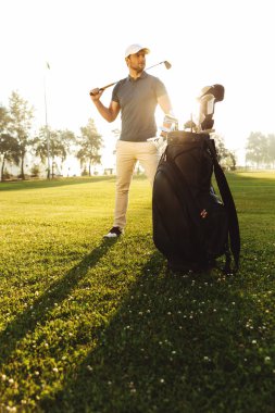 Yeşil alan üzerinde duran genç erkek golfçü