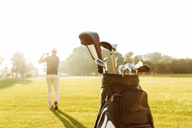 Arkadan görünüşü golf kulüp sallanan bir erkek golfçü