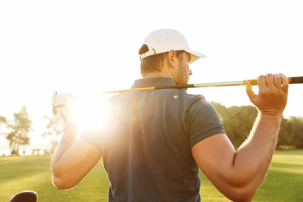 Vista trasera de un joven que lleva un palo de golf —  Fotos de Stock