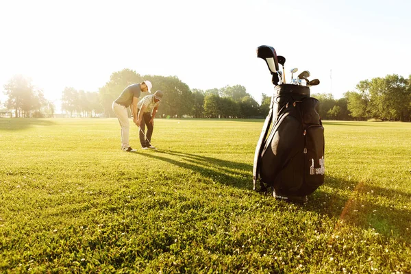 Entrenador masculino senior enseñando a deportista joven cómo jugar al golf —  Fotos de Stock