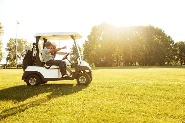 Deux golfeurs masculins conduisant dans une voiturette de golf — Photo