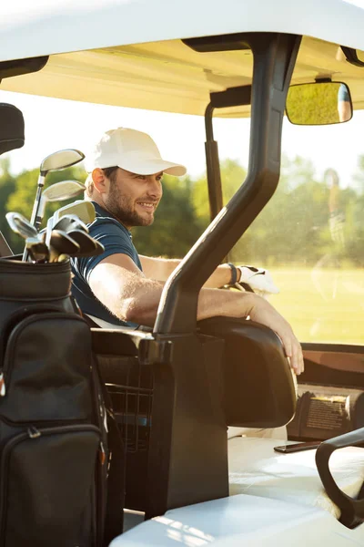 Bir golf arabası içinde oturan erkek golfçü gülümseyen