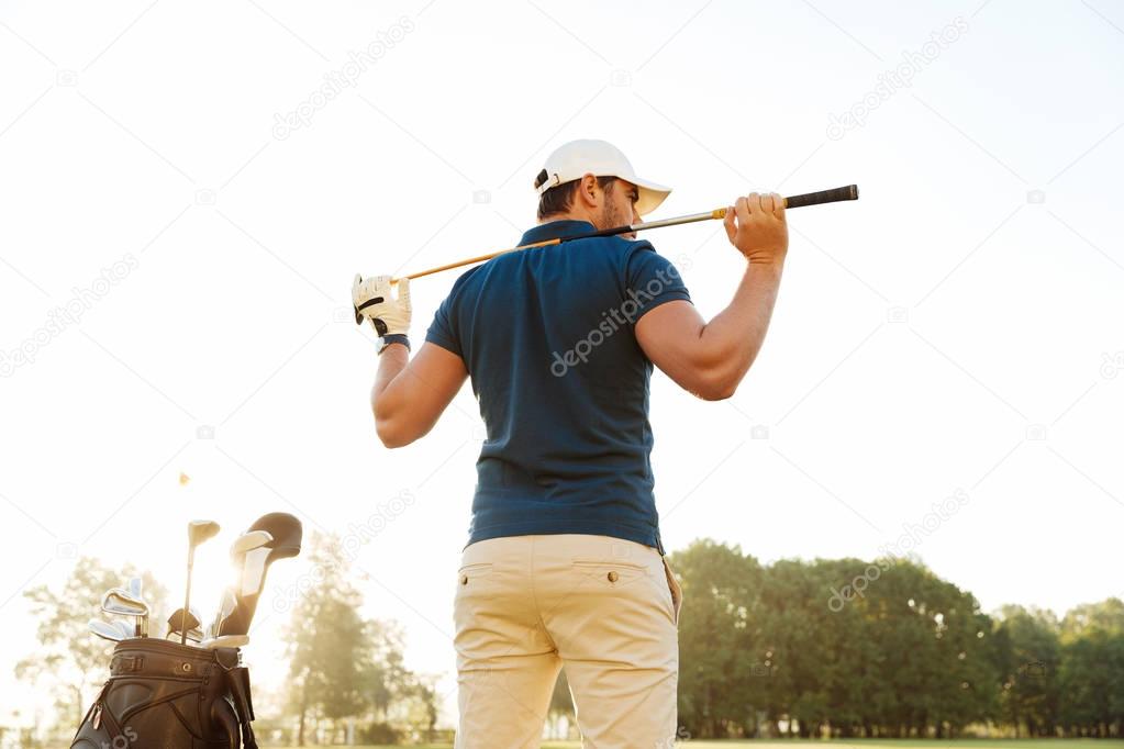 Back view of a male golf player at the course with a club sack