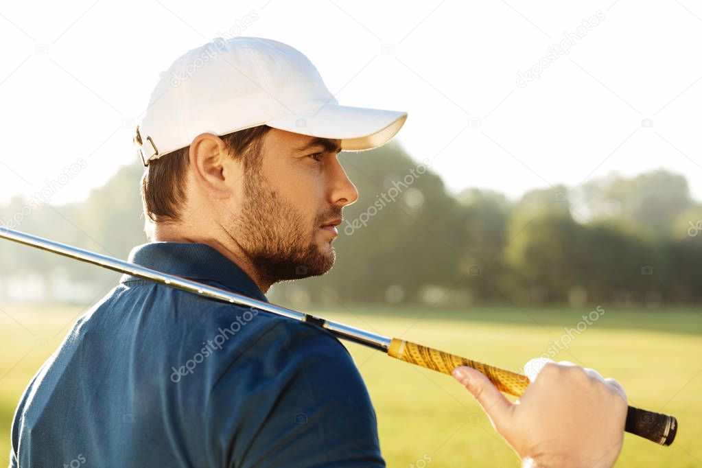 Close up of a young handsome male golfer in hat