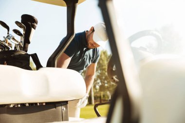Golf arabası duran genç erkek golfçü