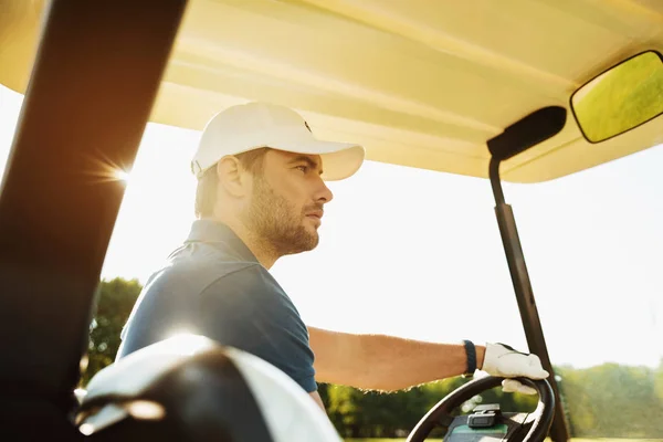 Male golfer driving a golf cart