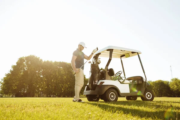 Golfista tomando palos de una bolsa en un carrito de golf —  Fotos de Stock