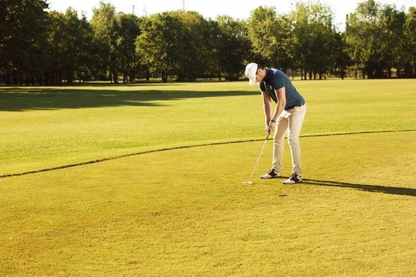 Чоловік гольф кладе м'яч для гольфу на зелений — стокове фото