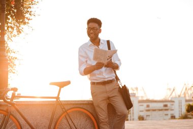 Yakışıklı genç Afrika adam sabah gazetede bisiklet ile.