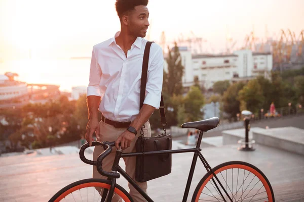 Konzentrierter junger Afrikaner frühmorgens mit Fahrrad — Stockfoto