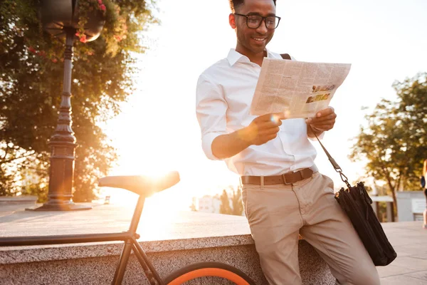 アフリカ系のハンサムな若者は新聞を読んで自転車で早朝を男します。. — ストック写真