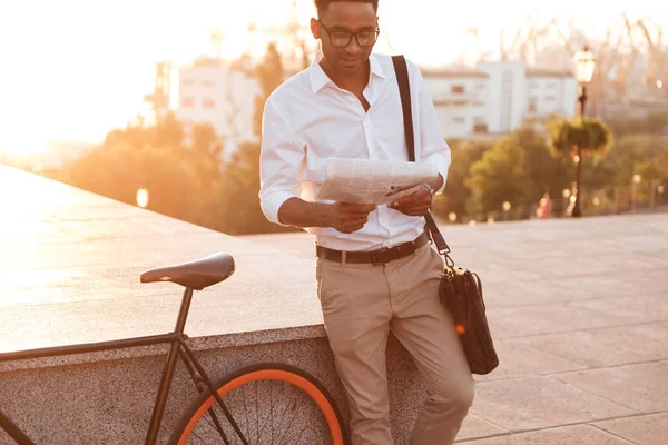 アフリカ系のハンサムな若者は新聞を読んで自転車で早朝を男します。. — ストック写真