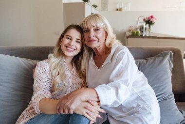 Büyükannesi ile birlikte bir kanepede oturan mutlu gülümseyen kız