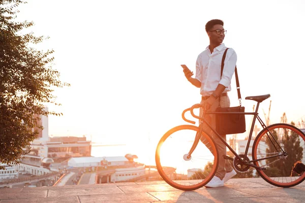 Homem africano de manhã cedo de pé perto de bicicleta — Fotografia de Stock