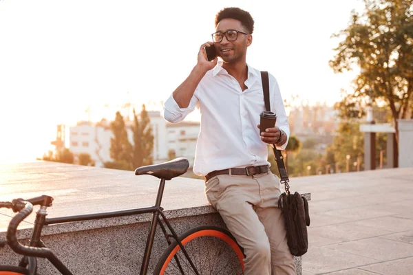 Çekici genç Afrika adam sabah telefonla konuşurken bisiklet ile. — Stok fotoğraf