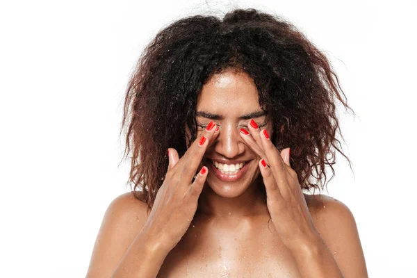 Glückliche junge Afrikanerin putzt ihr Gesicht mit Wasser. — Stockfoto