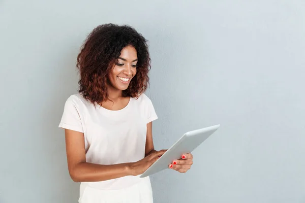 Bastante joven afroamericana mujer de pie y usando tableta — Foto de Stock