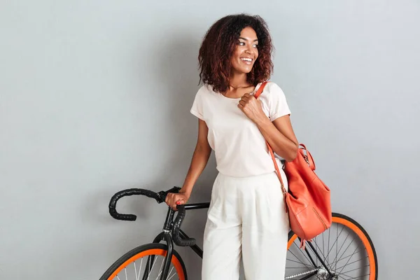 Sorrindo mulher africana posando com bicicleta e mochila — Fotografia de Stock