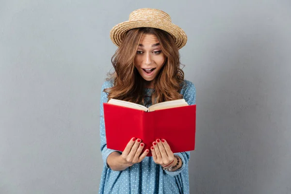 Geschokt mooie jongedame lezen van een boek. Op zoek naar opzij. — Stockfoto