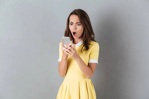 Geschokt verrast meisje op zoek naar mobiele telefoon met de mond open — Stockfoto