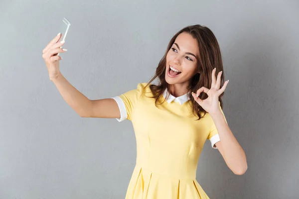 Bella ragazza mostrando gesto ok mentre prende un selfie — Foto Stock